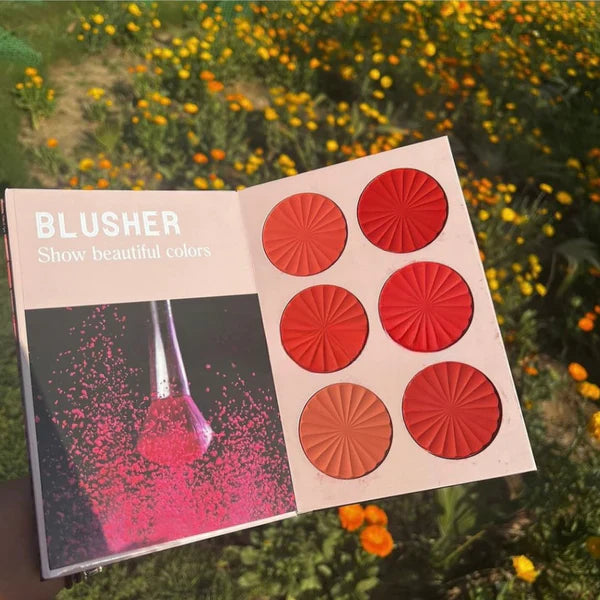 Makeup palette with red and pink shades against a natural background